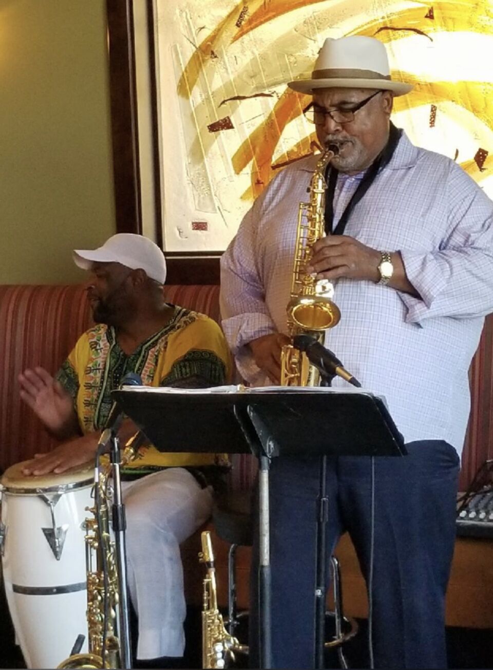 Ron Burris performing with a percussionist against a golden mural