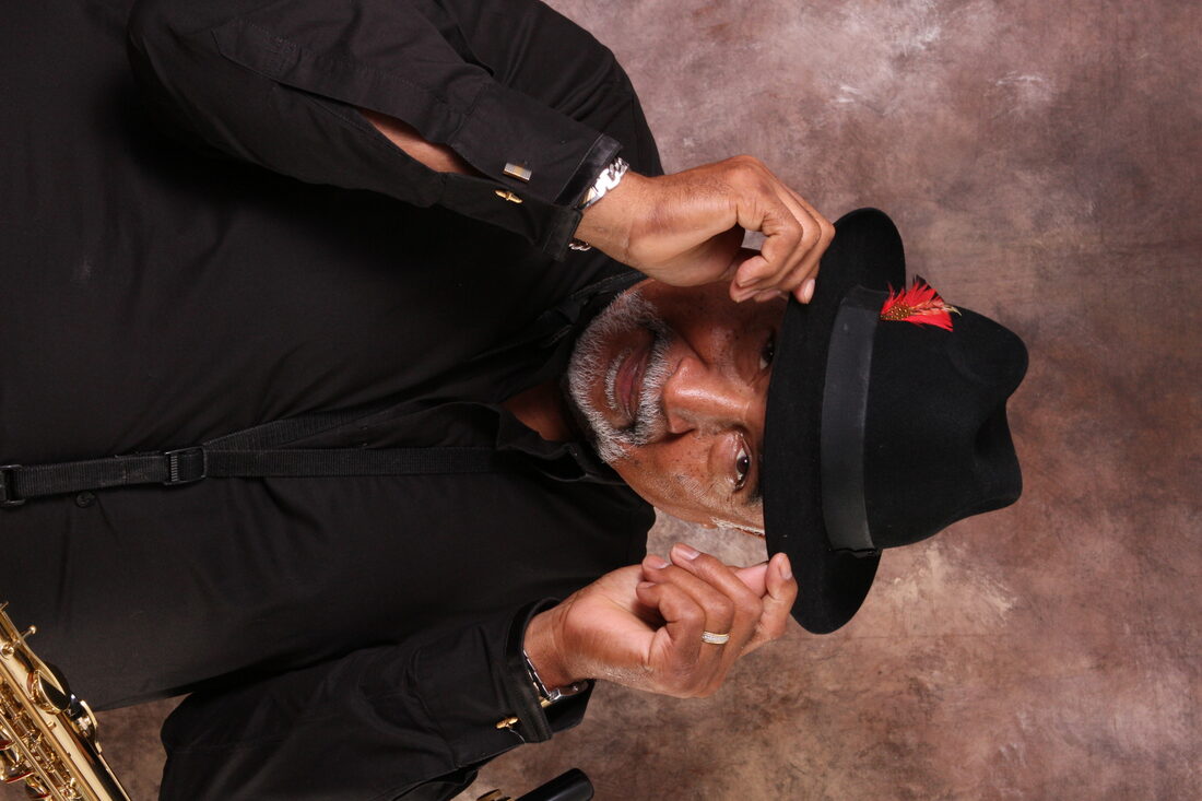 Studio portrait of Ron Burris in a black hat with red feather